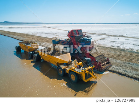 Heavy machinery works along the banks of Baskunchak Lake, actively extracting salt and transporting it into large trucks. Heavy machinery works along the banks of Baskunchak Lake, actively extracting salt and transporting it into large trucks. 126727999