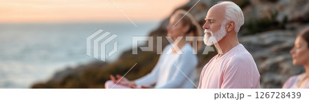 Participants engage in group meditation led by a senior yoga instructor on a breathtaking cliff overlooking the ocean, enveloped in soft sunrise mist at a luxury wellness retreat 126728439