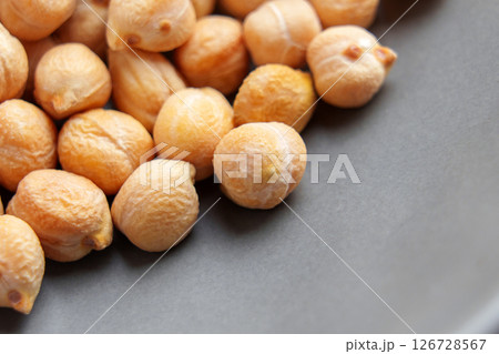 Dry chickpea beans on black ceramic plate surface. Macro. Uncooked protein fiber diet ingredient. Dry chickpea beans on black ceramic plate surface. Macro. Uncooked protein fiber diet ingredient. 126728567