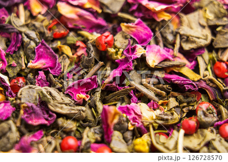 Falling leaves and petals of green herbal flower tea with chamomile, hibiscus, red peppercorns. Macro shot. Falling leaves and petals of green herbal flower tea with chamomile, hibiscus, red peppercorns. Macro shot. 126728570