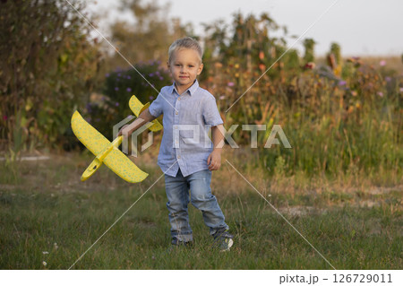 Little boy in the field plays with an airplane. Little boy in the field plays with an airplane. 126729011
