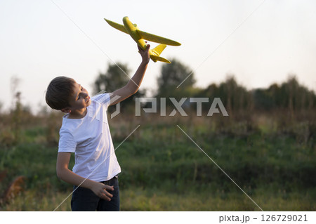 Little boy in the field plays with a yellow plane. 126729021