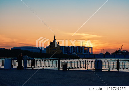 Sunset Silhouette: Two Women by Riverside, Cathedral, and Stadium Sunset Silhouette: Two Women by Riverside, Cathedral, and Stadium 126729925