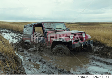 Modified off-road truck stuck in deep mud, driver using a winch to pull it free, determination in their eyes, embracing the thrill of wild, extreme adventure 126731234