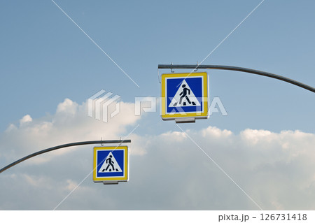 Two pedestrian crossing signs under blue sky close-up. Urban planning, traffic organization, road safety, infrastructure and transport design. 126731418