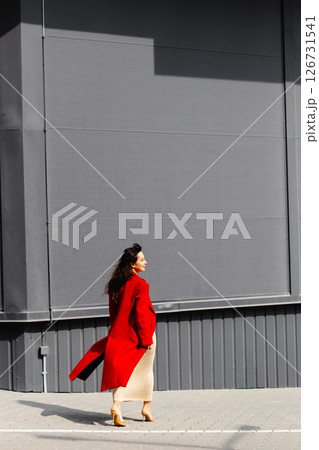 Businesswoman walking in the city wearing elegant red coat Businesswoman walking in the city wearing elegant red coat 126731541