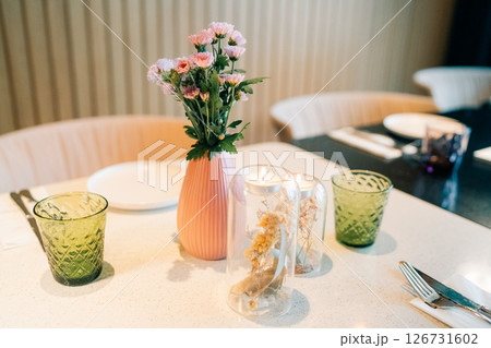Table setting with decorative vase and candle holders in a modern dining space during daylight 126731602