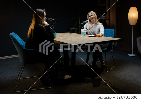 Two female podcasters recording a new episode in a professional studio Two female podcasters recording a new episode in a professional studio 126731680