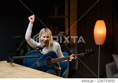 Singer playing guitar and singing with microphone in recording studio Singer playing guitar and singing with microphone in recording studio 126731692