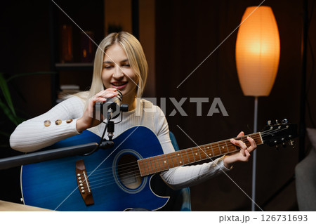 Young woman singing and playing acoustic guitar in recording studio Young woman singing and playing acoustic guitar in recording studio 126731693