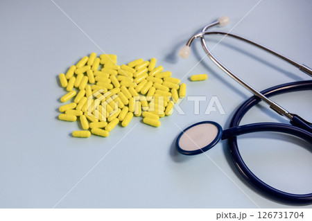 A bunch of yellow pills and stethoscope on a blue A bunch of yellow pills and stethoscope on a blue 126731704