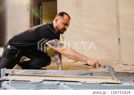 Construction Worker Cutting Ceramic Tile Using Tile Cutter in Bathroom Construction Worker Cutting Ceramic Tile Using Tile Cutter in Bathroom 126731826