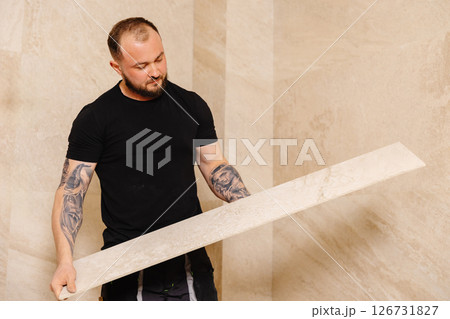 Construction Worker Installing Large Travertine Tiles in Modern Bathroom 126731827