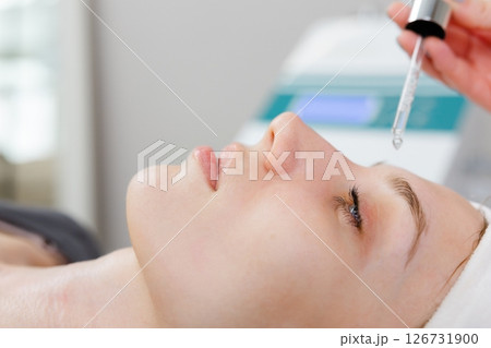 Beautician applying serum on face of young woman for skin care treatment 126731900