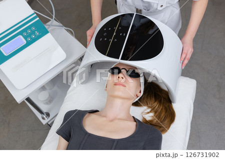 Beautician using led light therapy facial device on client for skin rejuvenation Beautician using led light therapy facial device on client for skin rejuvenation 126731902