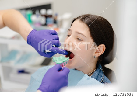 Dentist placing impression tray in girl's mouth for dental care Dentist placing impression tray in girl's mouth for dental care 126732033