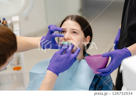 Dentist applying dental mold to young patient's teeth 126732034