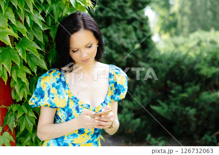 Portrait of a beautiful young woman standing at the green leaves tree Portrait of a beautiful young woman standing at the green leaves tree 126732063