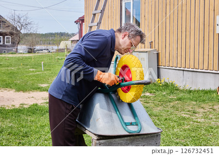 Conducting wheel fitting on hand cart, DIYer mounts polyurethane foam wheel to achieve long lasting operation and minimize risk of unexpected repairs. 126732451