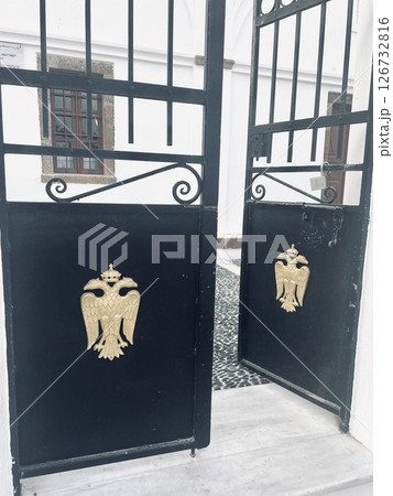 Black metal doors with a bird emblem - entrance to a church near the fortress in Santorini Black metal doors with a bird emblem - entrance to a church near the fortress in Santorini 126732816