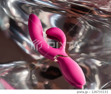 Sex toy on a metal background in the reflections of light.  126733131