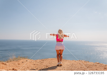 A woman stands on a beach looking out at the ocean A woman stands on a beach looking out at the ocean 126733195