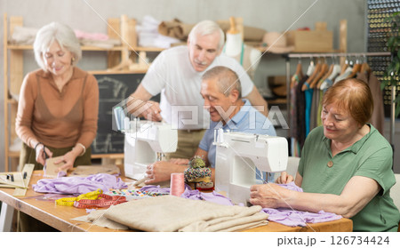 Elderly men and women spending time sewing in workroom 126734424