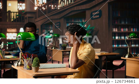Tired frustrated university student struggling to memorize information on the papers, trying to learn class notes for an upcoming exam. Stressed pupil with lack of motivation. Camera A. Tired frustrated university student struggling to memorize information on the papers, trying to learn class notes for an upcoming exam. Stressed pupil with lack of motivation. Camera A. 126734661