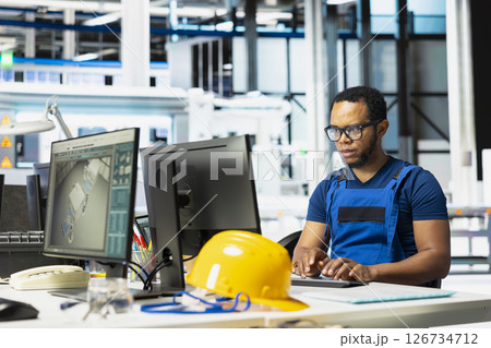 African american technician analyzing energy consumption software in solar factory, uses PC program to enhance solar cells production and reduce technical issues in automated machinery systems. African american technician analyzing energy consumption software in solar factory, uses PC program to enhance solar cells production and reduce technical issues in automated machinery systems. 126734712