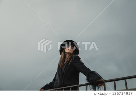 Woman Watching Over The Railing Admiring The Natural Landscape Below The Town  126734917