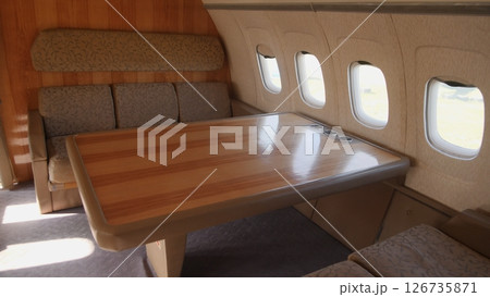 Luxurious Aircraft Interior Featuring a Spacious Seating Area and Elegant Wooden Table, Perfect for Relaxation or Meetings on Long Flights 126735871