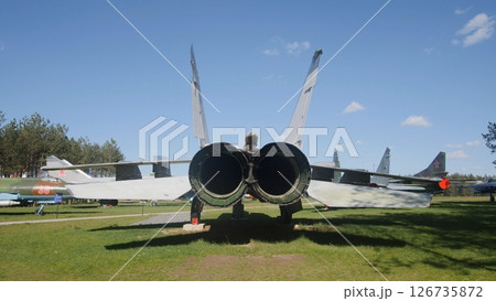 Military Aircraft on Display at an Outdoor Aviation Exhibition Surrounded by Green Grass and Blue Skies in a Park Setting 126735872