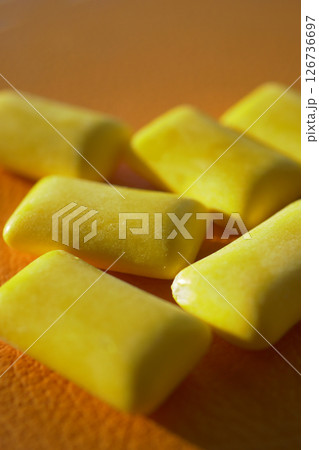 Yellow gum pieces scattered on an orange surface 126736697