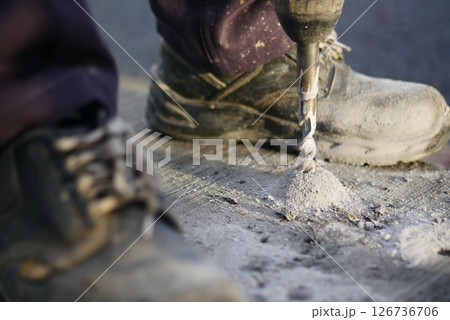 Worker drills into concrete surface at construction site Worker drills into concrete surface at construction site 126736706