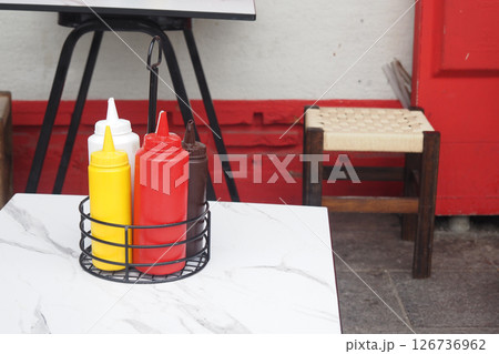 Condiment bottles on a table in vibrant outdoor setting Condiment bottles on a table in vibrant outdoor setting 126736962