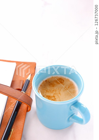 ミルクをたっぷり入れたコーヒー、カフェ・ラッテを飲みながら、システム手帳でデスクワーク中のイメージ ミルクをたっぷり入れたコーヒー、カフェ・ラッテを飲みながら、システム手帳でデスクワーク中のイメージ 126737000