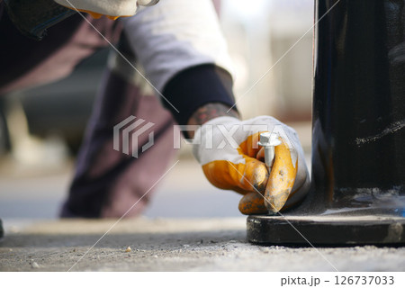 Worker tightening bolts on street fixture in urban area 126737033