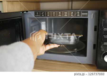 Heating a meal in the microwave at home kitchen Heating a meal in the microwave at home kitchen 126737080