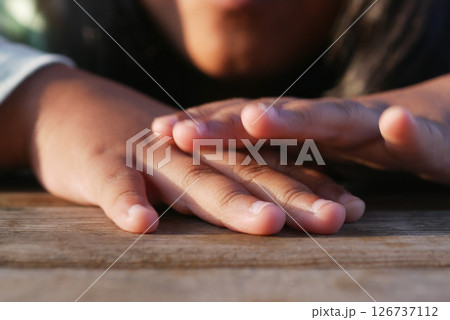 Hands resting on a wooden surface during golden hour 126737112