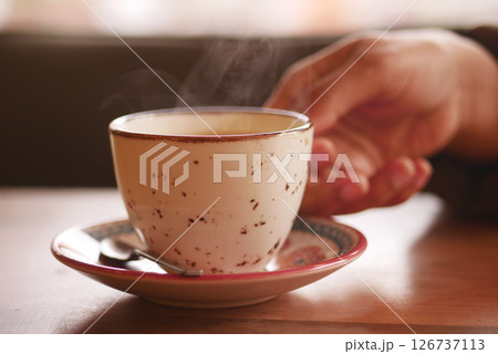 Warm cup of coffee on a cozy table in a cafe Warm cup of coffee on a cozy table in a cafe 126737113