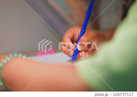 Child writing with blue pen at a table during study time Child writing with blue pen at a table during study time 126737117