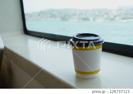 Coffee cup on a windowsill with a waterfront view Coffee cup on a windowsill with a waterfront view 126737123