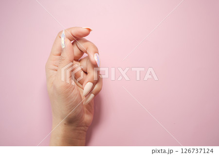 A hand showcases a beautiful manicure with pastel colors on pink A hand showcases a beautiful manicure with pastel colors on pink 126737124