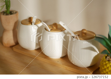 Ceramic jars with wooden lids on a wooden display board 126737152