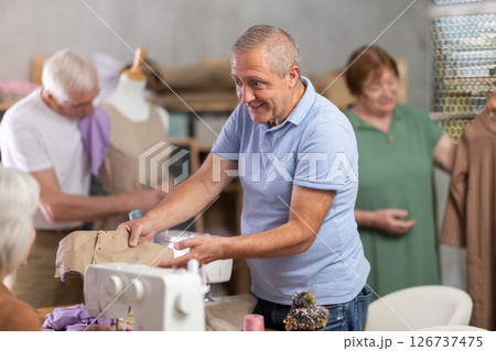 Man discussing pattern with female classmate during sewing course for older adults Man discussing pattern with female classmate during sewing course for older adults 126737475