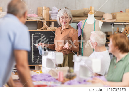 Elderly female teacher conducts master class on sewing 126737476