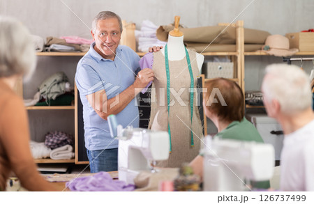 Aged sewing instructor teaching garment modeling using dress form 126737499