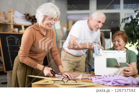 Woman cutting fabric along pattern during sewing session for seniors Woman cutting fabric along pattern during sewing session for seniors 126737592