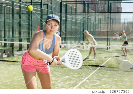 Young woman looking back after the ball while playing Padel Tennis in tennis court 126737593
