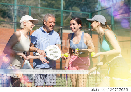 Mature husband and wife with their daughters talking before padel game 126737626